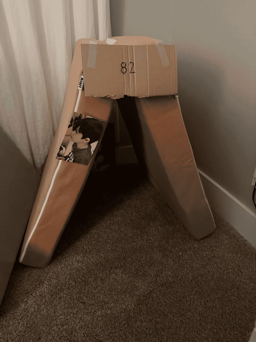 Room 82: an orange cushion tent with a cardboard sign reading 82